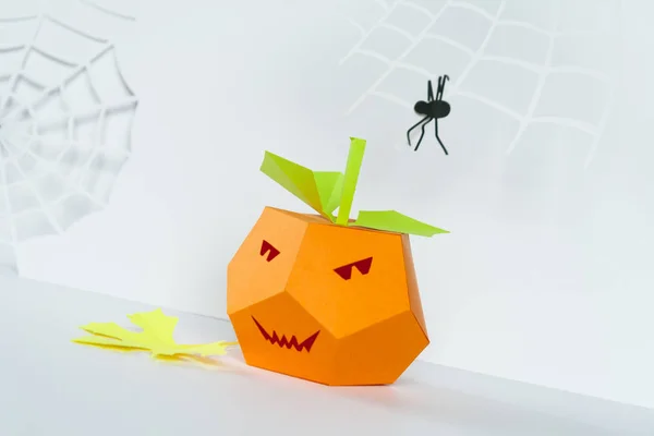 Happy Halloween. Halloween decor made of paper. Pumpkin and spider weaves its web made of paper