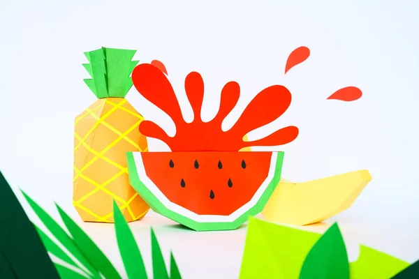Banana and penapple and splash from watermelon cut from paper with tropical leaves on white background