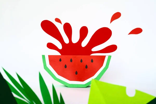 splash from watermelon cut from paper with tropical leaves on white background