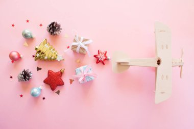 Eko kavramı. Ahşap çocuk uçak pembe bir arka plan üzerinde farklı Noel dekorasyonu ile. Yeni yıl kavramı.