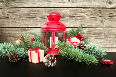 Neşeli Noel ve mutlu yeni yıl. Kırmızı Noel Fener çam dalları, hediyeler ve bir ahşap zemin üzerine kırmızı meyveler