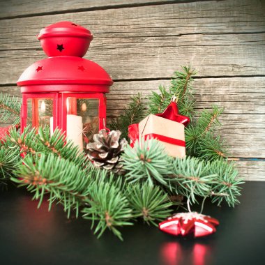 Neşeli Noel ve mutlu yeni yıl. Kırmızı Noel Fener çam dalları, hediyeler ve bir ahşap zemin üzerine kırmızı meyveler