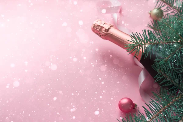 Neşeli Noel kavramı. Şişe champange köknar çorbaları ve Noel topları ve pembe bir arka plan üzerinde pembe kurdele ile.