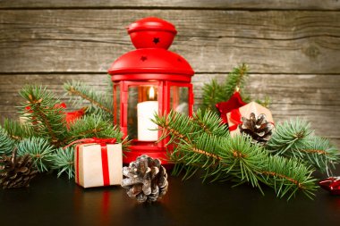 Neşeli Noel ve mutlu yeni yıl. Kırmızı Noel Fener çam dalları, hediyeler ve bir ahşap zemin üzerine kırmızı meyveler