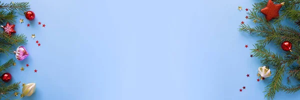 Mutlu Noeller ve mutlu yeni yıl. Neşeli Noel kartı yeşil çam dalları ve tatil nesne üzerinde mavi arka plan ile. Web için uzun biçim