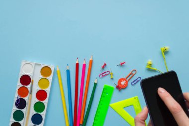 Çeşitli ileti örneği ve mavi arka plan telefonda. Telefonunu onun elinde tutan. Geri okul kavramı.