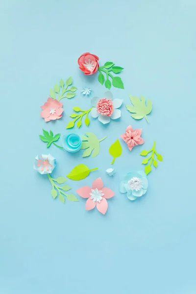 Mutlu Paskalyalar. Paskalya yumurtası kağıt çiçekler mavi zemin üzerine yapılmış. Kağıttan kesilmiş.