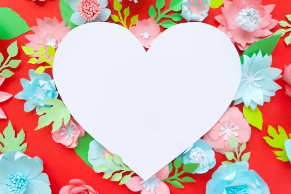 Heart frame with paper flowers with green leaves on red background. Cut from paper. Valentines day concept