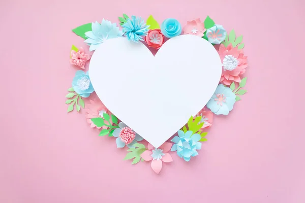 Heart frame with paper flowers with green leaves on pink background. Cut from paper. Valentines day concept