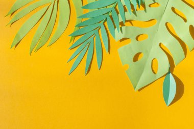 Yeşil tropikal yaprakları sarı bir arka plan üzerinde güneş ışınları gazetede kesilmiş. Yaz konsepti