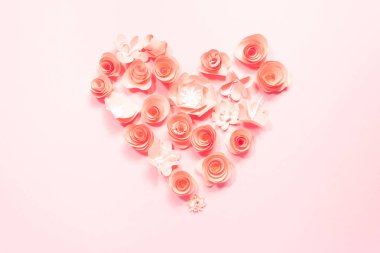 Gül kağıt çiçekler pembe bir arka plan üzerinde kalp.