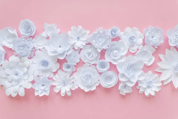 White paper flowers on pink background. Floral background cut from paper