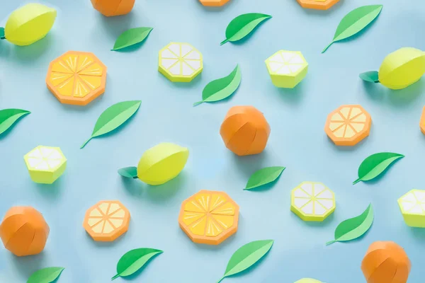 Pattern of fruit made of paper. Blue background. There\'s room for writing. Tropics. Flat lay. Orange, lemon and mandarine, summer concept