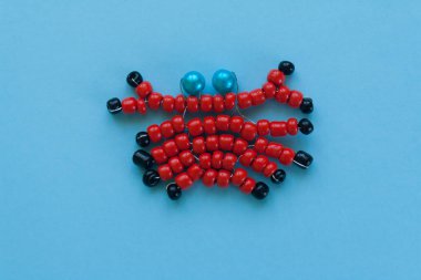 boncuk, mavi bir arka plan üzerinde çocuk el sanatları yapılan Yengeç.