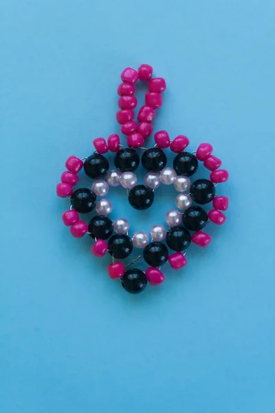 Heart made of beads, children's crafts on a blue background. — Stock Photo, Image