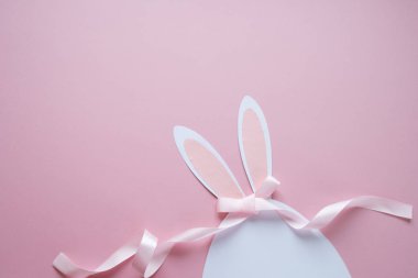 Mutlu paskalyalar. Kağıt üzerinde pembe bir arka plan Paskalya yumurtası yapılmış.