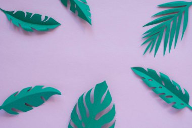 pembe arka planda kağıt kesilmiş tropikal yaprakları.