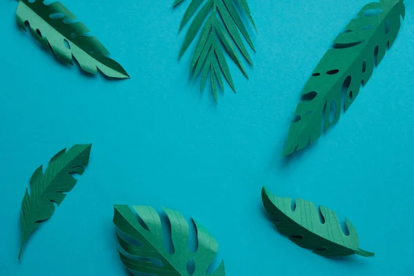 Hojas tropicales cortadas de papel sobre un fondo azul . — Foto de Stock