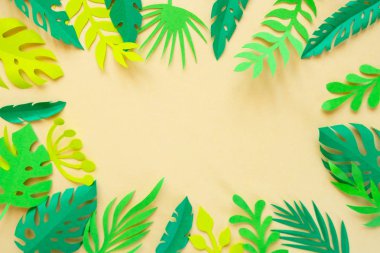 sarı bir arka planda kağıt kesilmiş tropikal yaprakları.