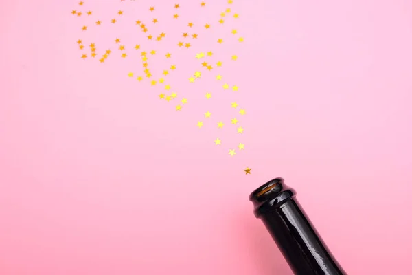 Salute from sequins in the form of stars flies out of a bottle of champagne — Stock Photo, Image