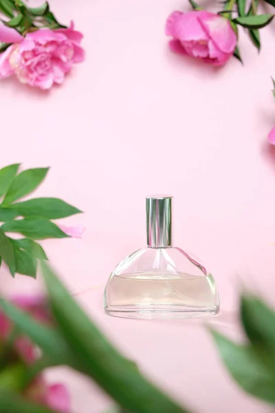 Butelka perfum na różowym tle z pięknymi piwonie. Pojęcie smaku. — Zdjęcie stockowe
