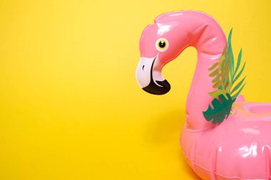 Parlak sarı arka planda şişme pembe flamingolar.