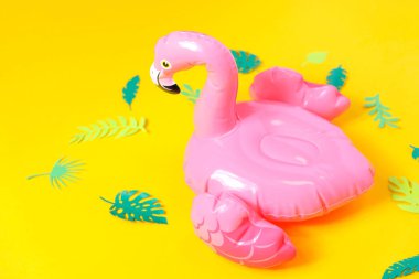 Parlak sarı arka planda şişme pembe flamingolar.