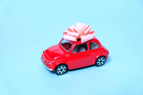 O carro vermelho está amarrado com um laço de presente. O conceito de um presente . — Fotografia de Stock