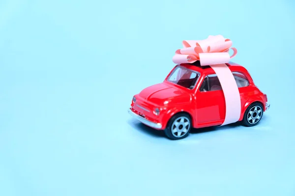 O carro vermelho está amarrado com um laço de presente. O conceito de um presente . — Fotografia de Stock