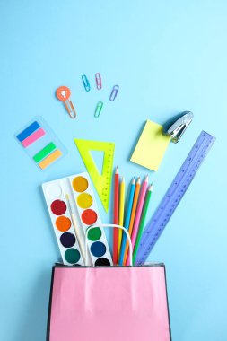 Okula geri dön. Açık mavi arka plan üzerinde çeşitli kırtasiye.