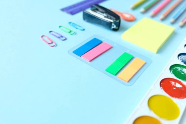 Okula geri dön. Açık mavi arka plan üzerinde çeşitli kırtasiye.