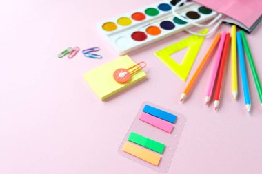 Okula geri dön. Açık pembe arka plan üzerinde çeşitli kırtasiye.