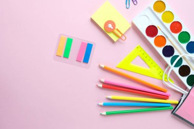 Okula geri dön. Açık pembe arka plan üzerinde çeşitli kırtasiye.