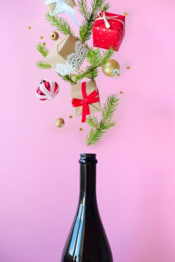 Pembe arka planda farklı noel dekorasyonu ile Şampanya şişesi.