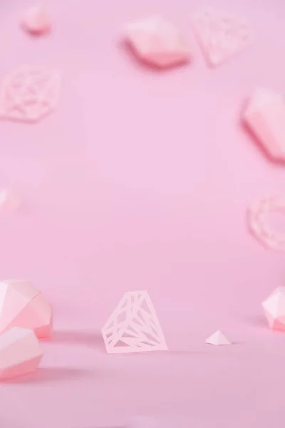 Una variedad de piedras preciosas facetadas, hechas de papel sobre un fondo rosa . — Foto de Stock