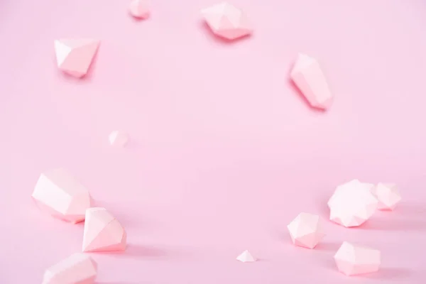 En mängd olika mångfacetterade ädelstenar, gjorda av papper på en rosa bakgrund. — Stockfoto
