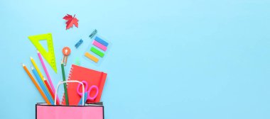 Okula geri dön. Açık mavi arka plan üzerinde çeşitli kırtasiye.