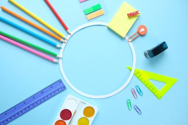 Mavi arka plan üzerinde renkli kalemler makas ile yuvarlak çerçeve, okul kavramına geri