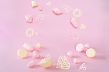 Pembe bir arka planda Kağıt yapılmış çok yönlü taşlar, çeşitli. Mücevher konsepti