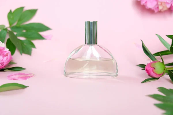 粉红色背景的香水瓶与美丽的牡丹。风味的概念. — 图库照片