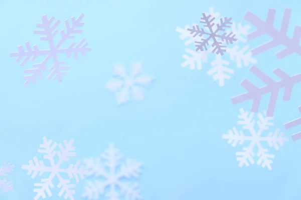Fundo de inverno. Flocos de neve brancos cortados de papel branco em um fundo azul . — Fotografia de Stock