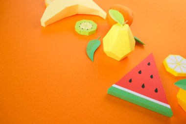 Kalın turuncu arka planda kağıttan yapılmış egzotik meyveler. Yaz konsepti.