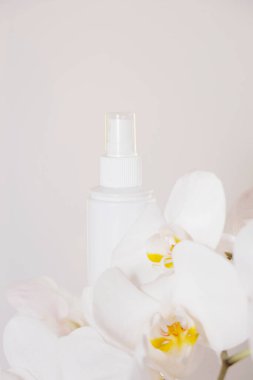 Beyaz arka planda beyaz orkide ile kozmetik ürünleri için gerçekçi beyaz boş tüpler. Krema tüpü.