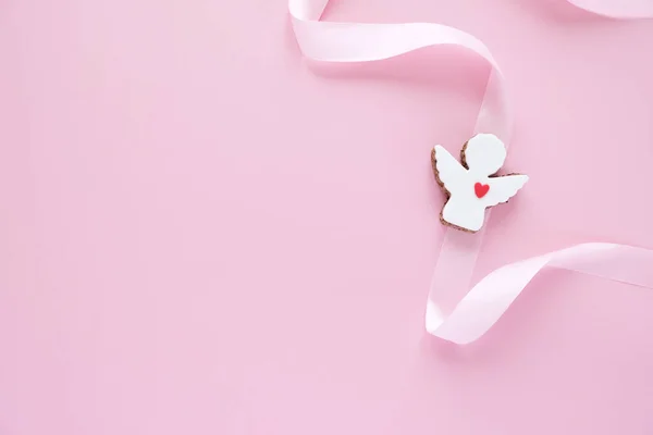 Biscotti a forma di angelo con nastro rosa su sfondo rosa. — Foto Stock