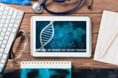 Beyaz tablet bilgisayar ve doktor aletleri ahşap masada.