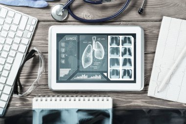 Beyaz tablet bilgisayar ve doktor aletleri ahşap masada.