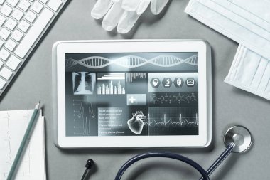 Gri yüzeyde beyaz tablet ve doktor araçları
