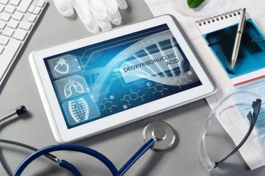 Gri yüzeyde beyaz tablet ve doktor araçları