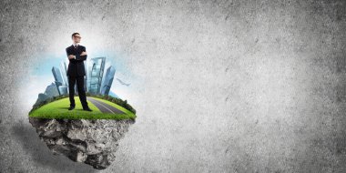 Yeşil yüzen adada beton zemine karşı duran kendine güvenen zarif iş adamı.