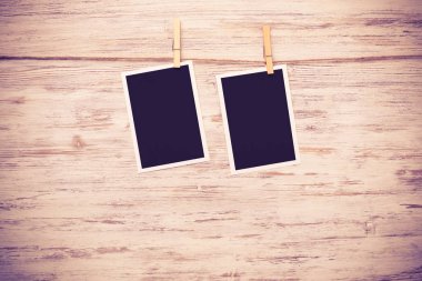 Boş fotoğraf çerçevesi ahşap bir zeminde ipte asılı.